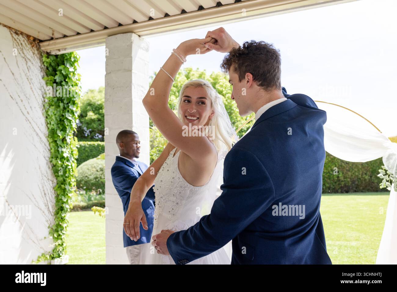 Braut und Bräutigam tanzen fröhlich bei einem Hochzeitsempfang im Freien und feiern die Liebe Stockfoto