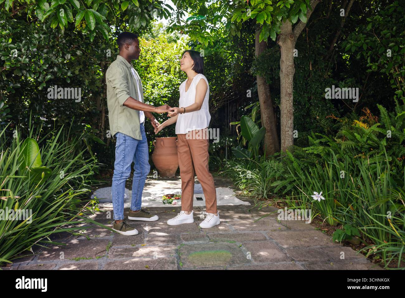 Afroamerikaner und asiatische Frau, die Hände im Garten halten, teilen sich Momente Stockfoto