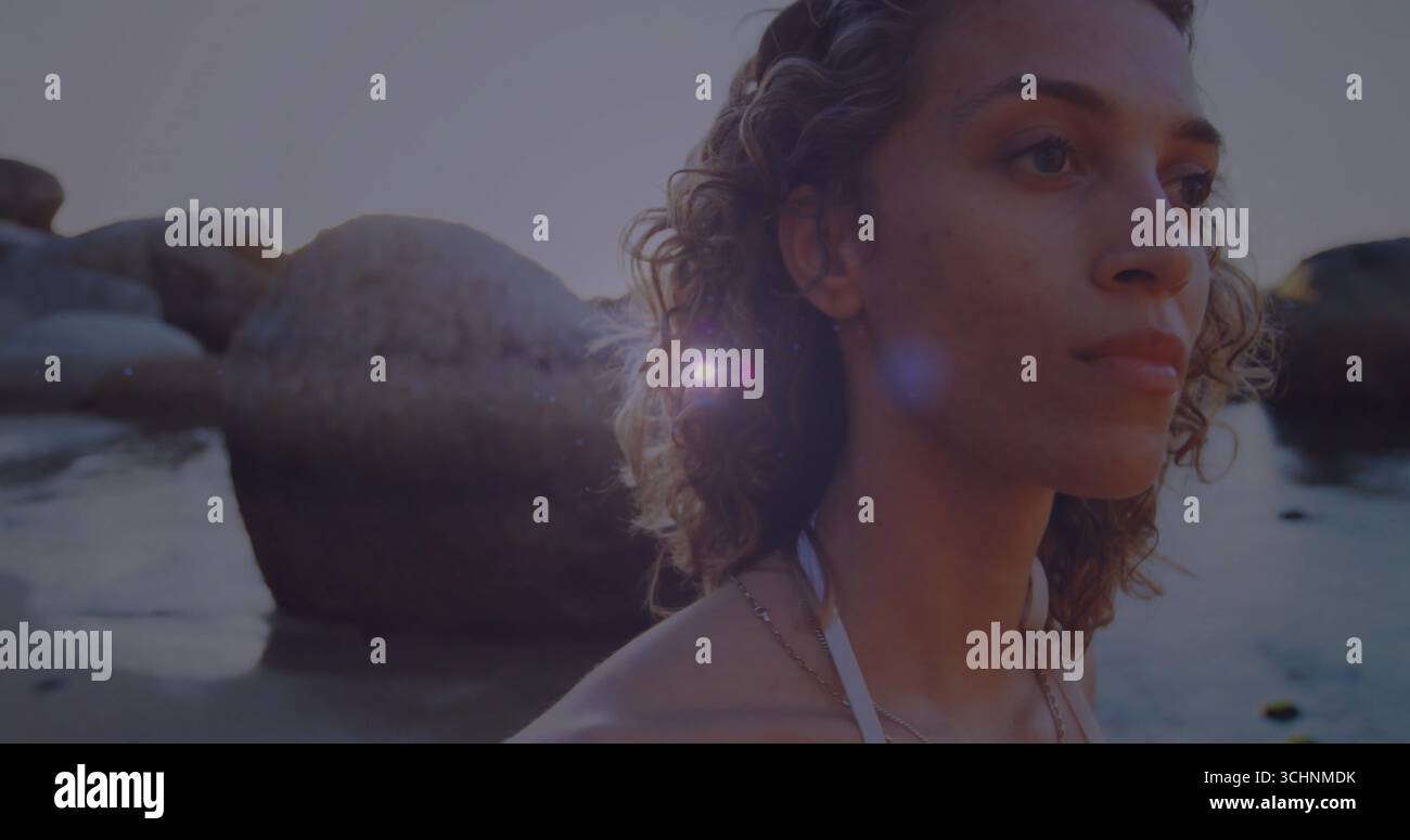 Watende Frau mit weißem Bikinioberteil und Halskette in der felsigen Strandbucht bei Sonnenuntergang, Kopierraum Stockfoto