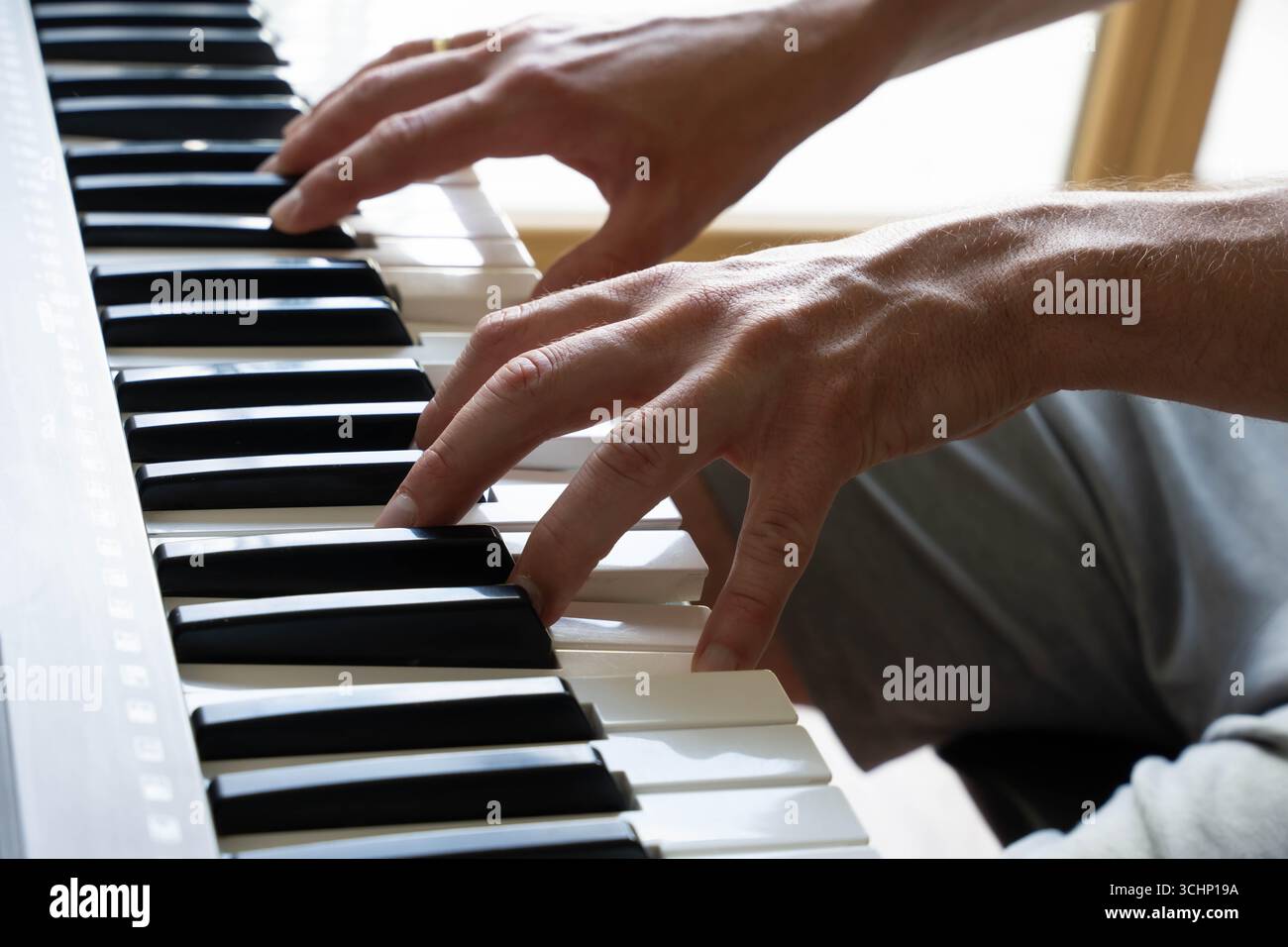 Nahaufnahme der Hände, die in Innenräumen Klavier spielen, und so Fokus, Präzision und künstlerisches Engagement zum Ausdruck bringen Stockfoto