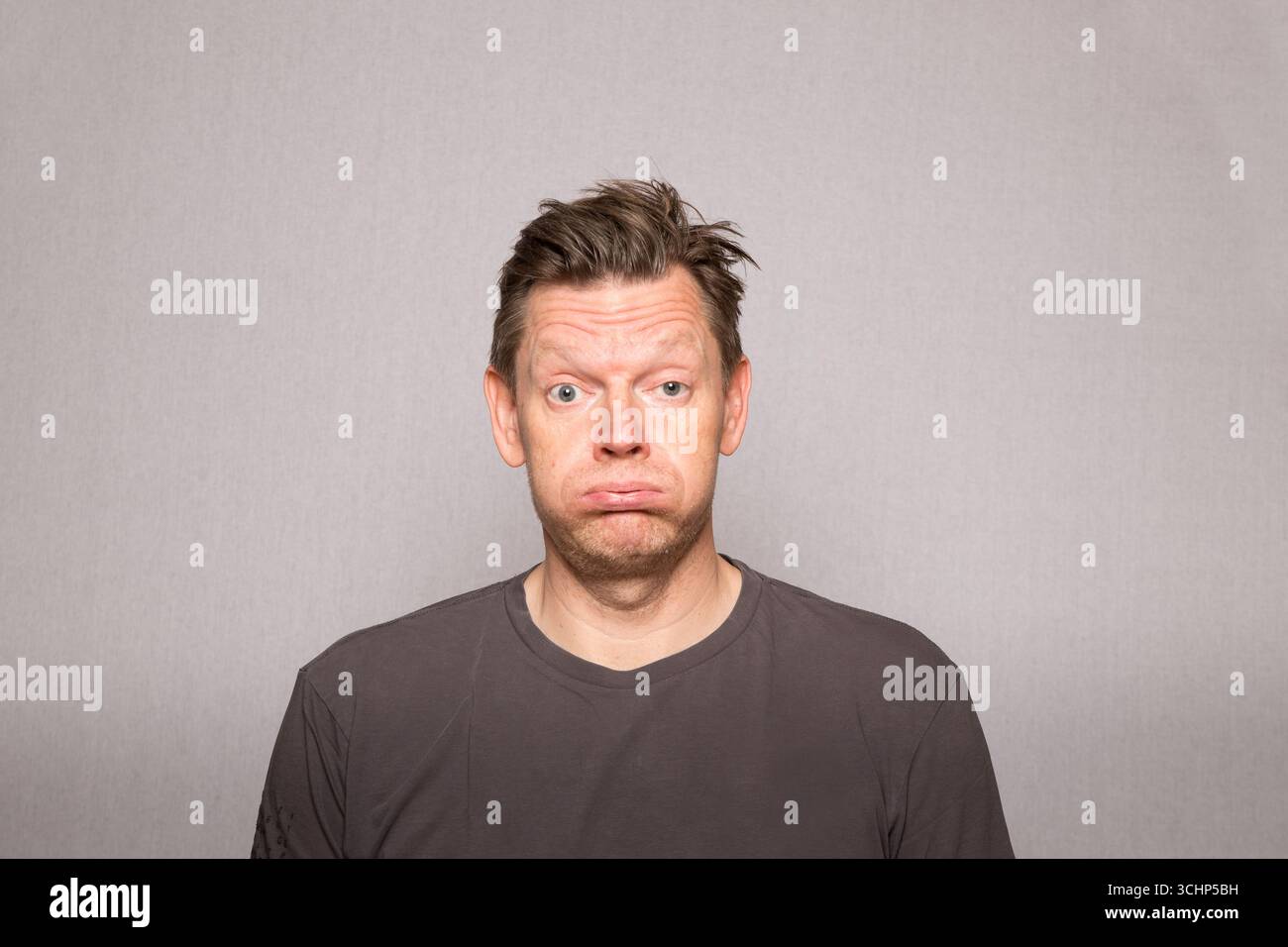 Sehr frustrierter Mann mit Gesichtsausdrücken auf Studiofoto mit grauem Hintergrund, frustrierter europäischer Mann mittleren Alters, Kopierraum Stockfoto