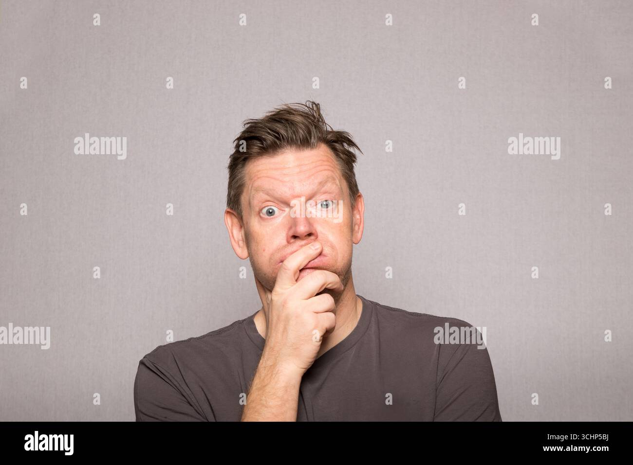 Sehr frustrierter Mann mit Gesichtsausdrücken auf Studiofoto mit grauem Hintergrund, frustrierter europäischer Mann mittleren Alters, Kopierraum Stockfoto