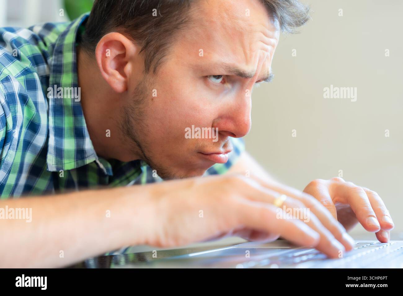 Frustrierter Mann, Der Sich Nach Vorne Beugt Und Den Laptop-Bildschirm Anstarrt, Während Er Von Zu Hause Aus Arbeitet Stockfoto