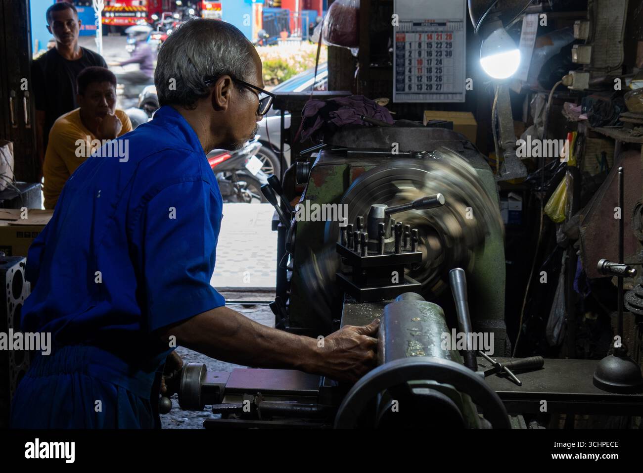 AMBON, INDONESIEN – 28. Mai: Ein Maschinenbauer verwendet eine Drehmaschine, um einen Motorblock in einer Maschinenfabrik in Ambon, Indonesien, am 28. Mai wieder aufzubereiten. Stockfoto