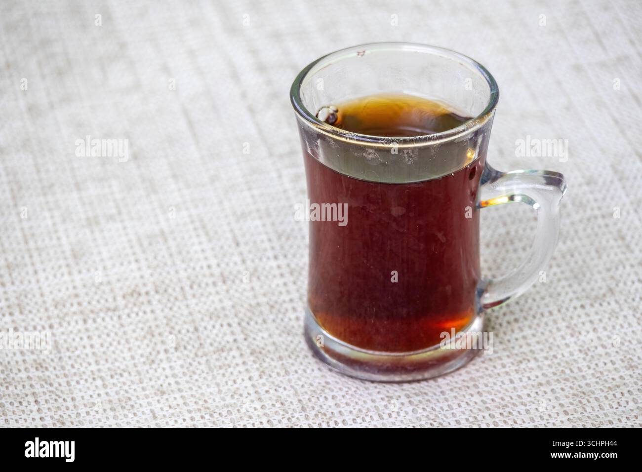 Schwarzer Tee oder roter Tee in einer Glasschale auf weißem strukturiertem Hintergrund. In Bangladesch heißt das Rong Cha oder Lal Cha. Stockfoto