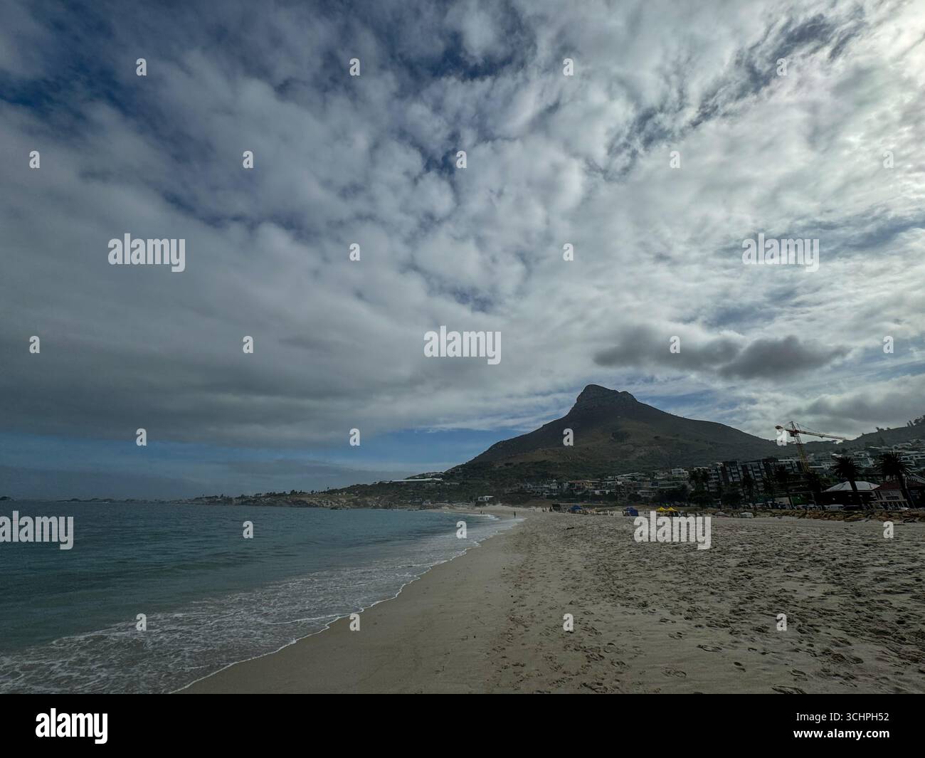 Eine Weitwinkelaufnahme eines Strandes in Kapstadt mit dem majestätischen Lion's Head Berg im Hintergrund. Das Foto zeigt den weiten Sandstreifen - Smartphone-aufgenommenes Stockfoto