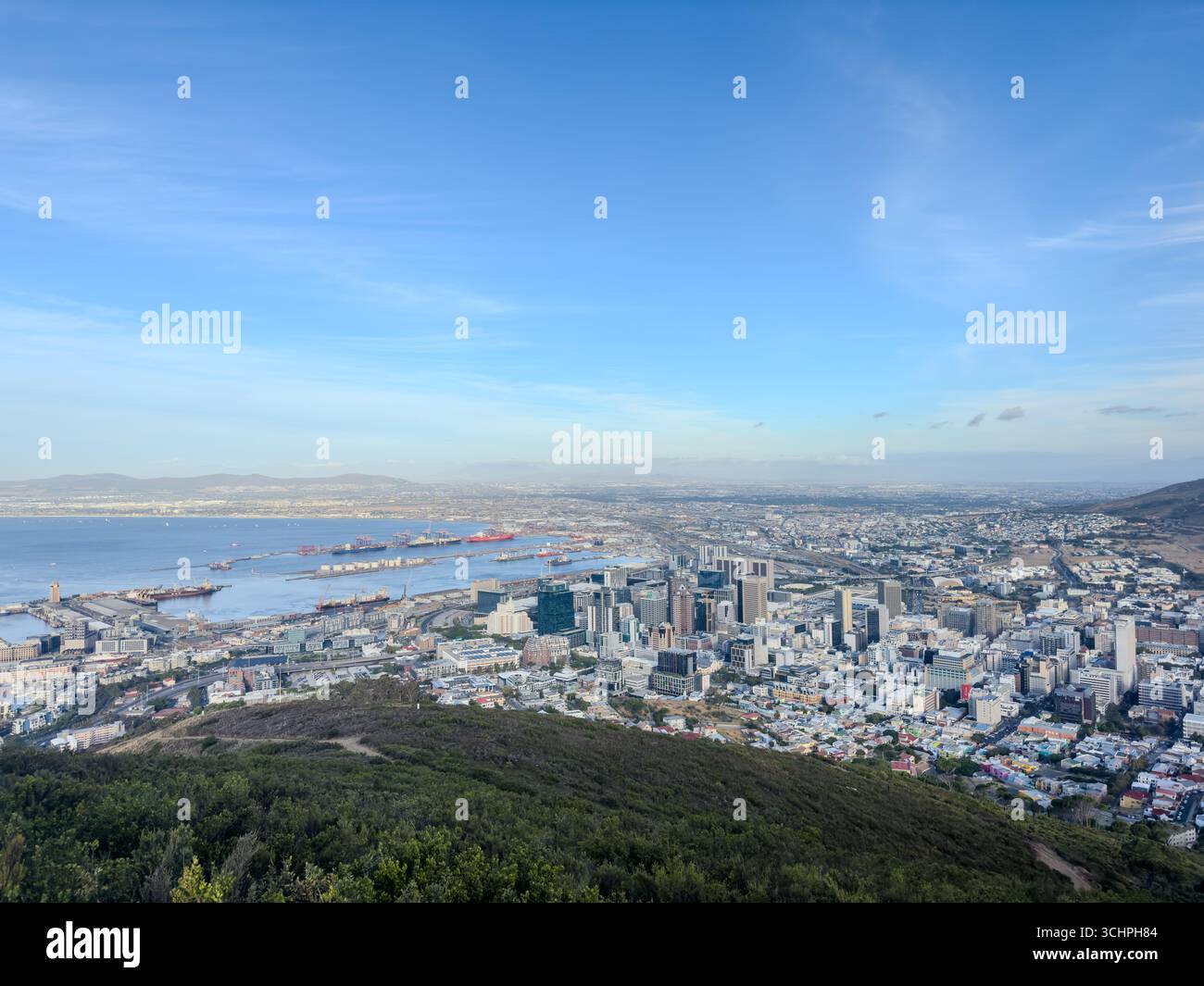 Ein atemberaubender Panoramablick auf den Kapstadt City Bowl, mit der pulsierenden Stadtlandschaft, die sich zum Meer hin erstreckt, und einem belebten Hafen. - Smartphone-aufgenommenes Stockfoto