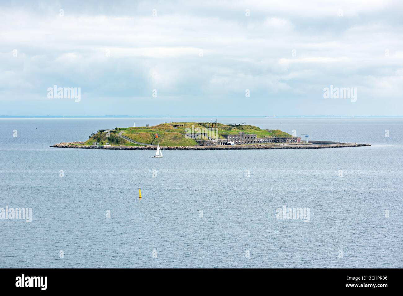 Flakfortet Island Øresund Charlottenlund Dänemark // CHARLOTTENLUND, Dänemark — Flakfortet, eine künstliche Insel und ehemalige Marinestützung, liegt in der Meerenge von Øresund vor der Küste von Charlottenlund. Ursprünglich zwischen 1910 und 1914 erbaut, sollte das Fort Kopenhagen verteidigen. Die Insel verfügt über eine zentrale Festung, die von einem Graben und einer kreisrunden Befestigungsmauer mit Kasernen und Waffenplatzierungen umgeben ist. Heute ist Flakfortet ein geschütztes Kulturerbe und ein beliebtes Ziel für Freizeitaktivitäten. Stockfoto