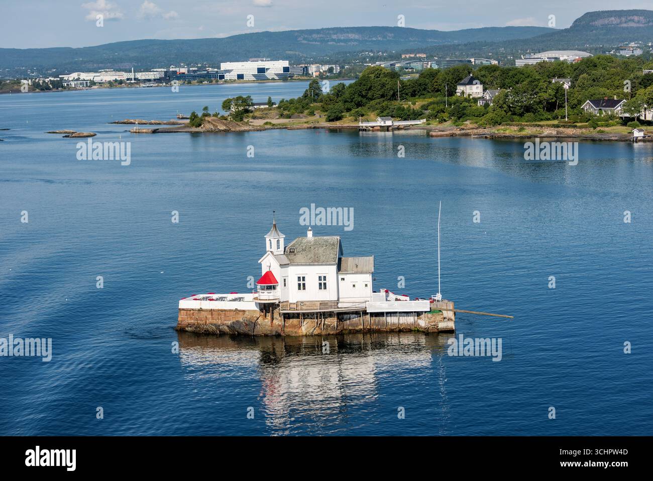 Dyna Fyr Leuchtturm Oslofjord Norwegen | LYSAKER, Norwegen — Dyna Fyr, erbaut 1874, steht im inneren Oslofjord vor der Küste von Lysaker in Akershus. Der außer Dienst gestellte Leuchtturm, der nun als privater Veranstaltungsort genutzt wird, zeigt ein ruhiges Profil auf dem offenen Wasser. Der innere Oslofjord ist hier belebt mit maritimem Verkehr, der zwischen dem Drøbak-Sund und dem Hafen von Oslo verkehrt, und Dyna Fyr bleibt ein Navigationslandmarke, selbst in seinem Ruhestand vom aktiven Dienst. Stockfoto