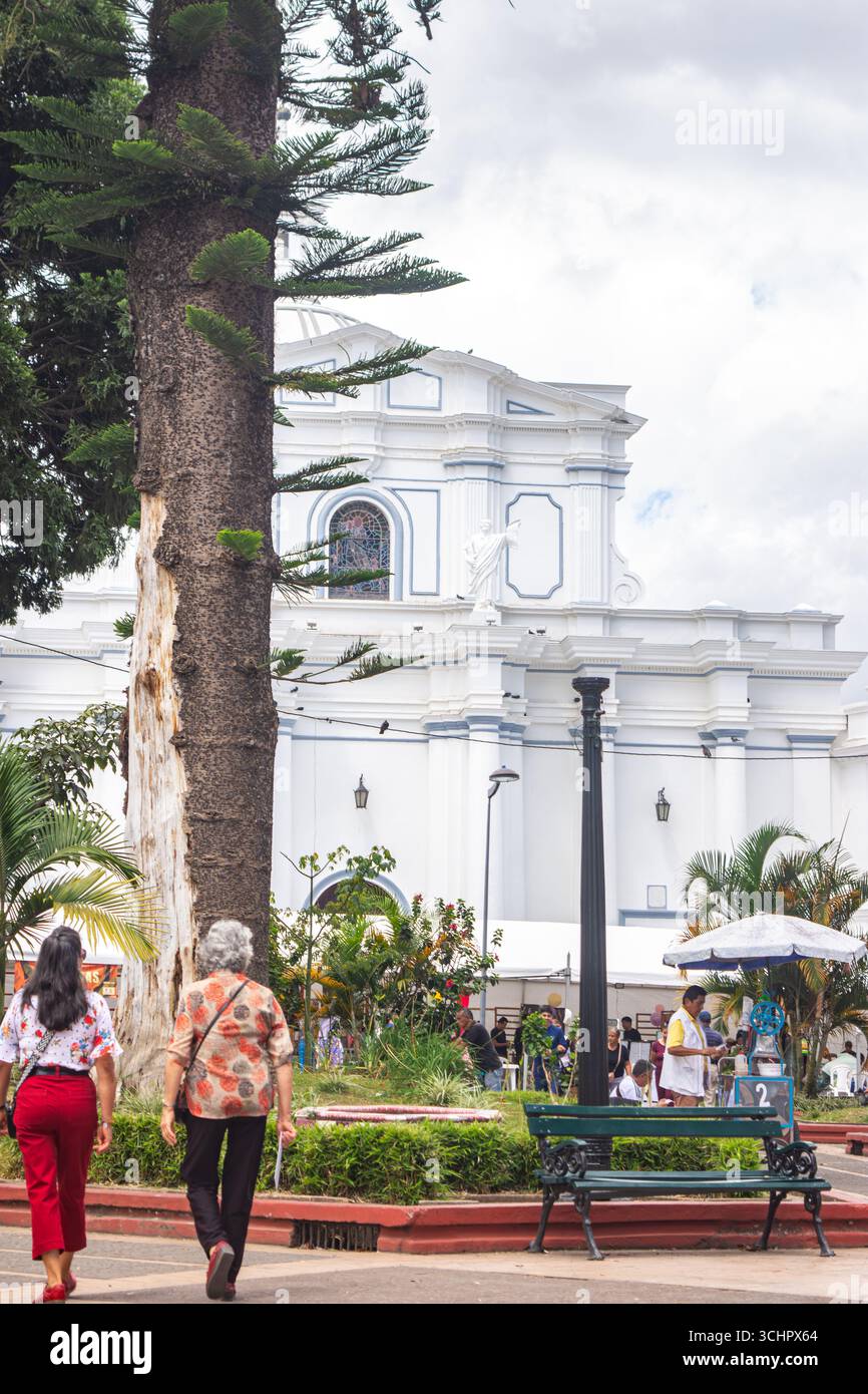 Eine malerische Aussicht auf eine Kirche in Popayán, Kolumbien, umgeben von üppigem Grün und Menschen, die das Parkambiente genießen. Stockfoto