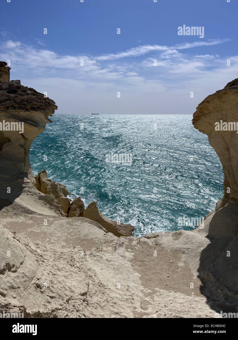Malerischer Blick auf den türkisfarbenen Persischen Golf, eingerahmt von zerklüfteten Sandsteinklippen unter einem hellblauen Himmel im südlichen Iran. Stockfoto