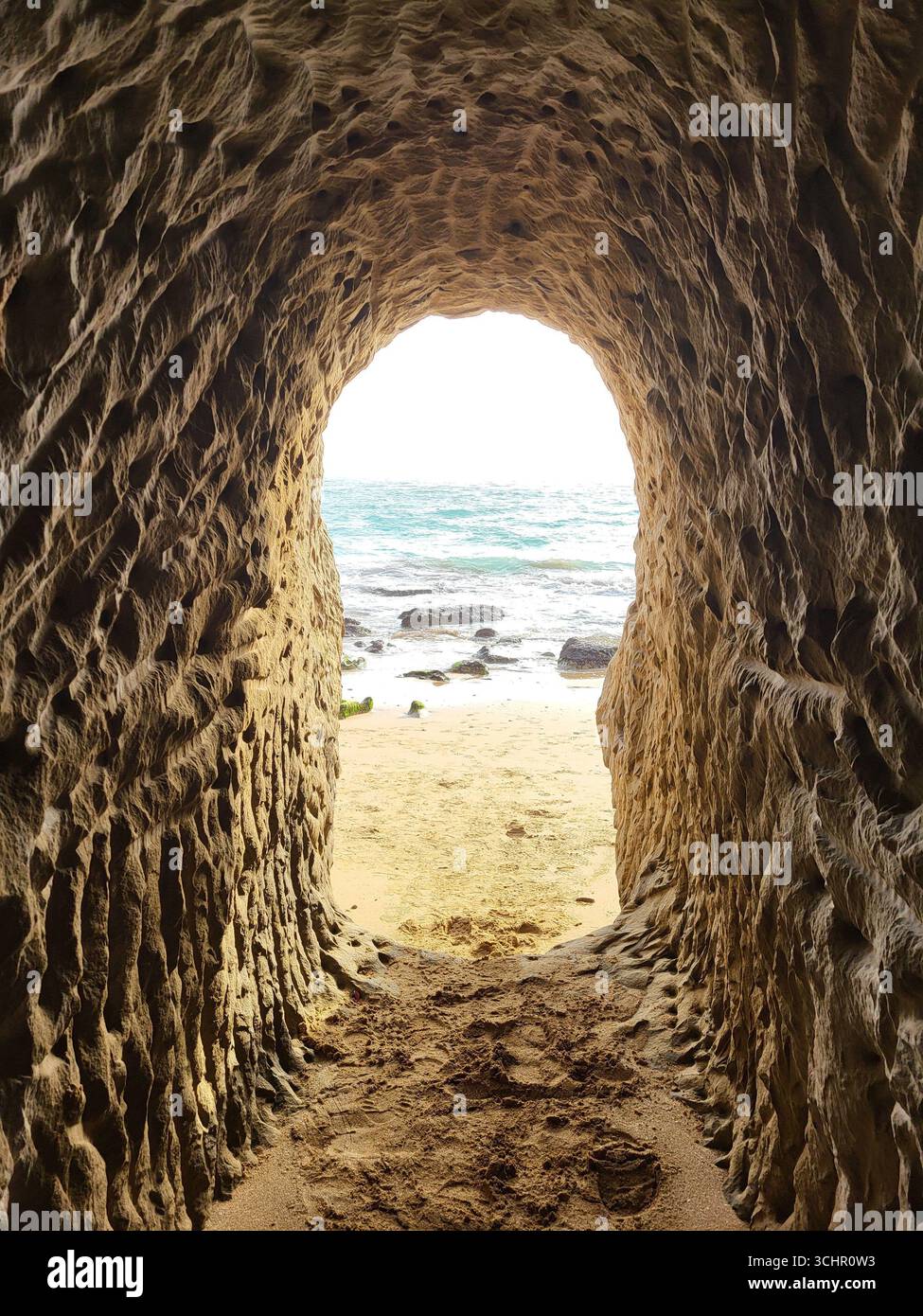 Blick aus dem Inneren einer handgeschnitzten Sandsteinhöhle, die sich auf den Strand der Lovers Gorge, Parsian, Südirans öffnet. Stockfoto Blick aus dem Inneren einer handgeschnitzten Sandsteinhöhle, die sich auf den Strand der Lovers Gorge, Parsian, Südirans öffnet. Stockfoto