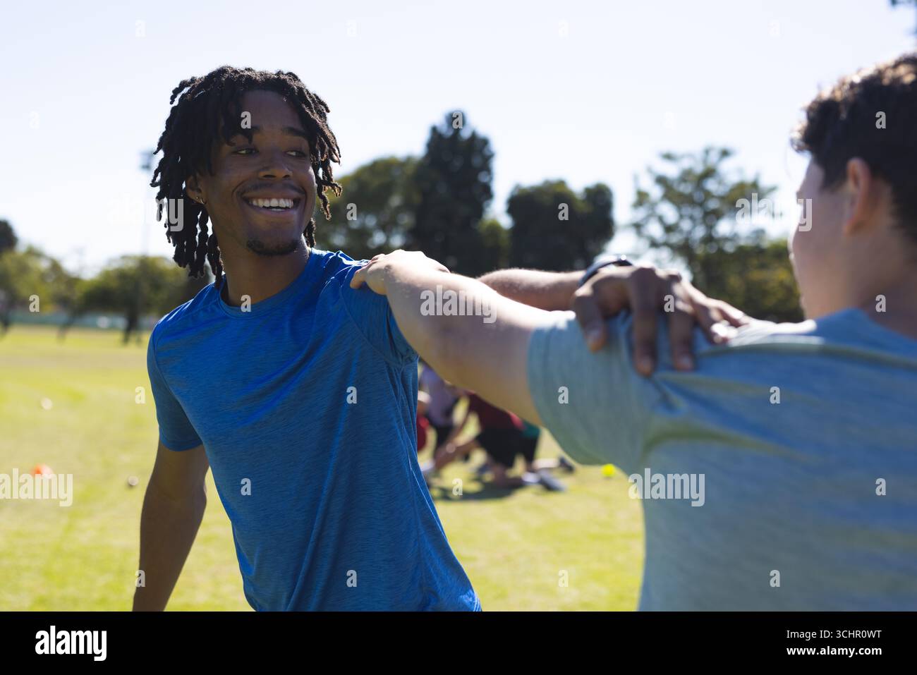 afroamerikaner dehnt sich mit Smartwatch-bekleideten Partner an Park-Trainingskegeln Stockfoto
