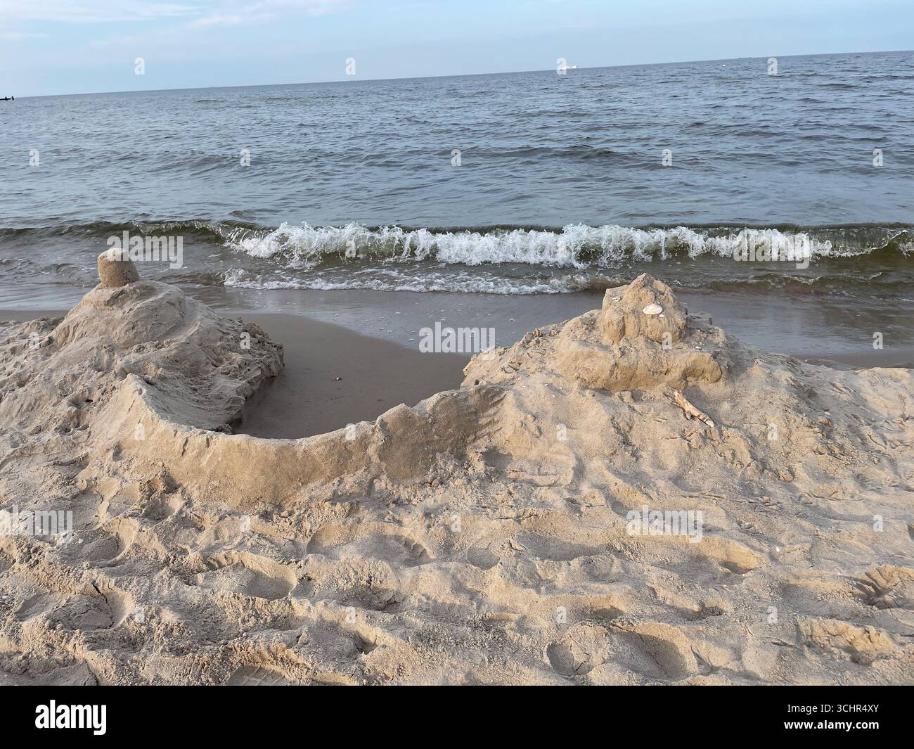 Sandburg, die von Wellen an einem Sandstrand weggespült wird. Foto: Willy Matheisl Stockfoto