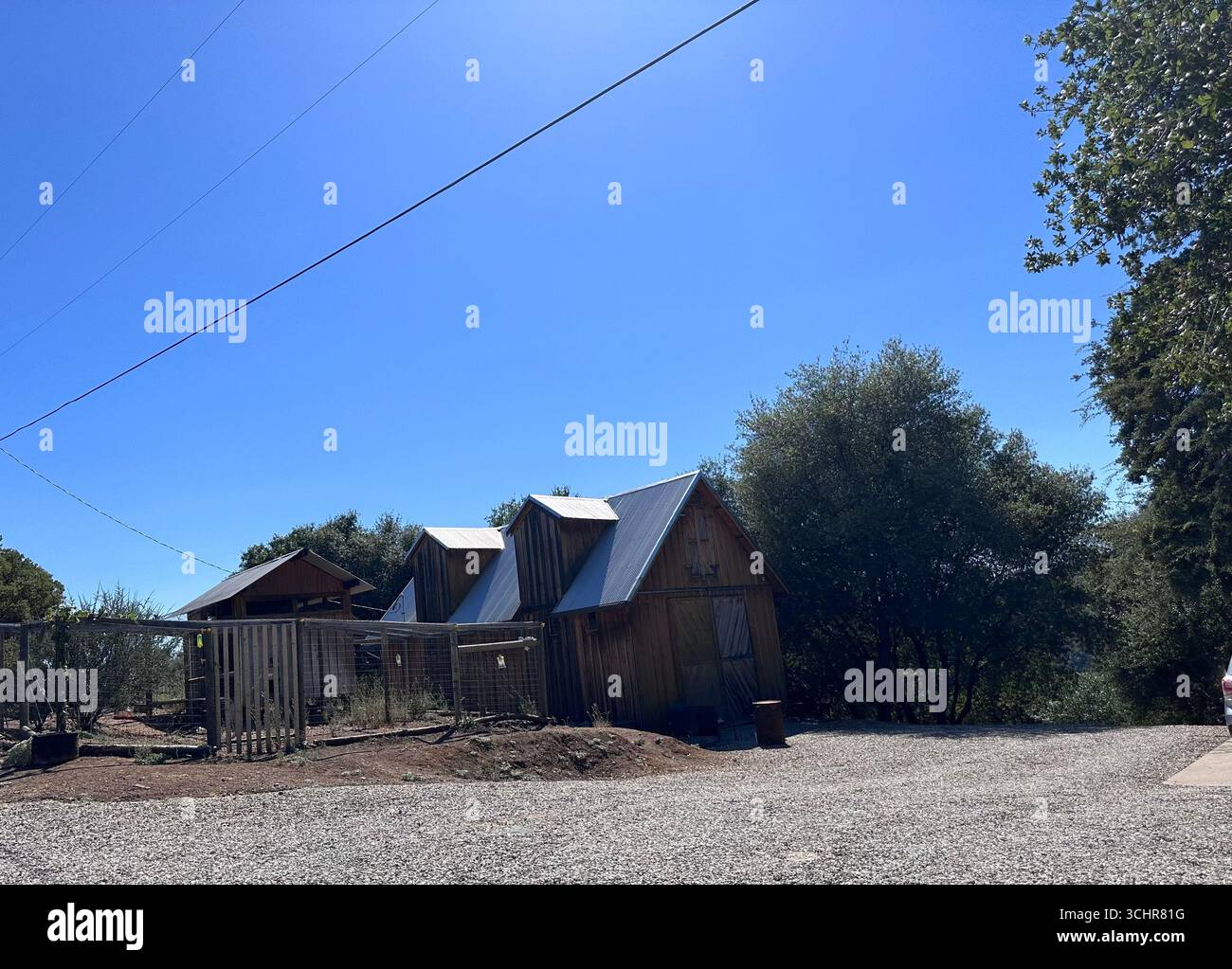 Kleine Holzhütten und Zäune in einer ländlichen Gegend unter klarem blauem Himmel in Kalifornien, USA. - Smartphone-aufgenommenes Stockfoto