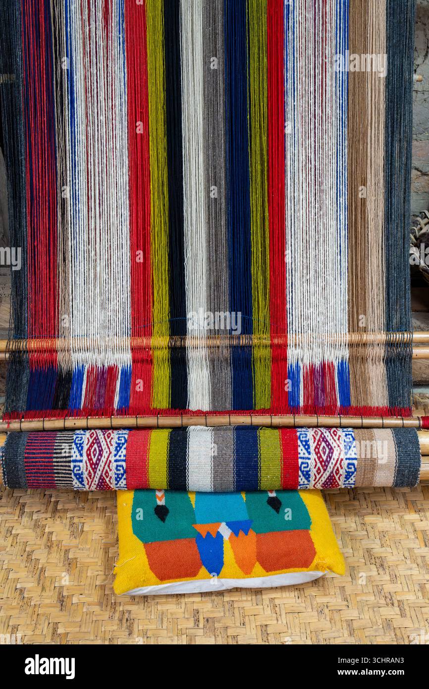 Ein traditioneller Webstuhl und eine Schilfmatte in der Tahuantinsuyo Weaving Workshop, Otavalo, Ecuador. Stockfoto