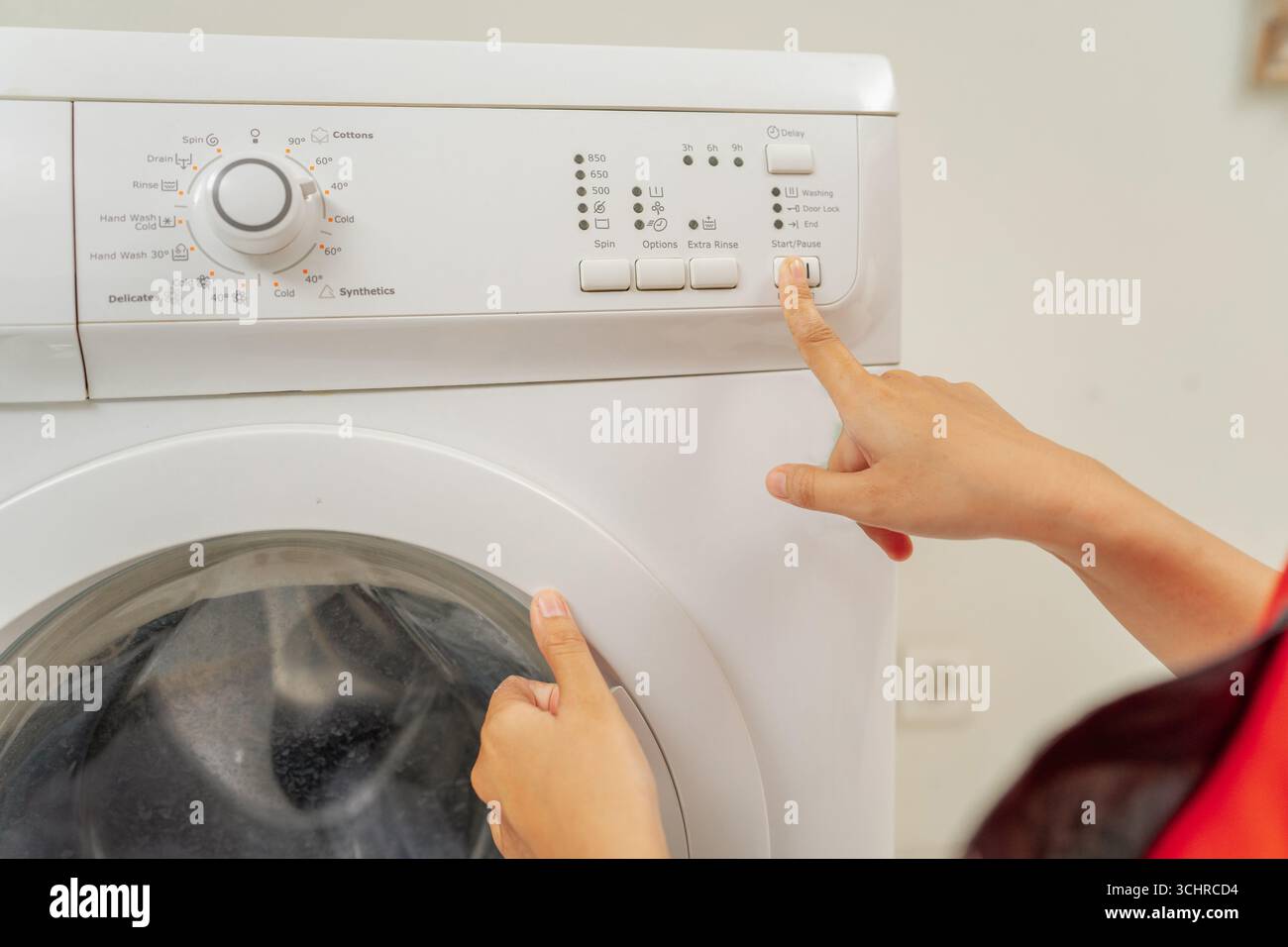 Benutzer, der mit dem Bedienfeld für die Einstellungen der Waschmaschinen interagiert Stockfoto