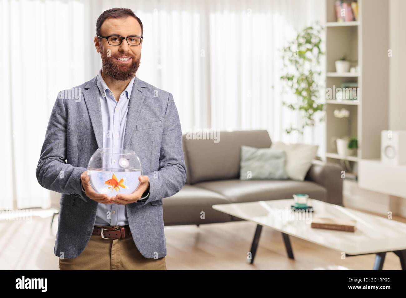 Ein Mann, der einen Goldfisch in einem Glasbehälter hält Stockfoto