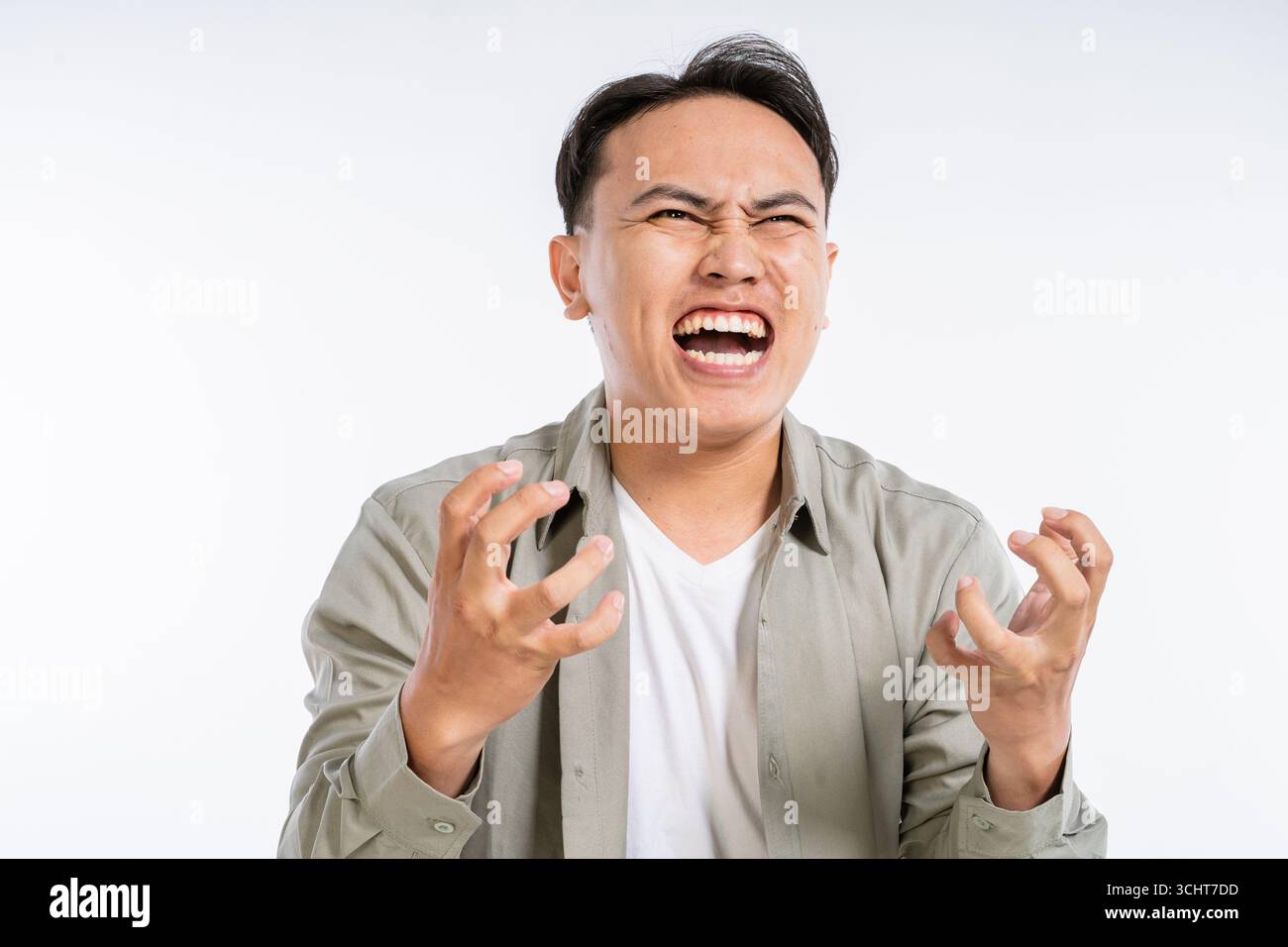 Ein frustrierter junger Mann drückt Wut aus in einem Studio mit einem Plain White Hintergrund Stockfoto