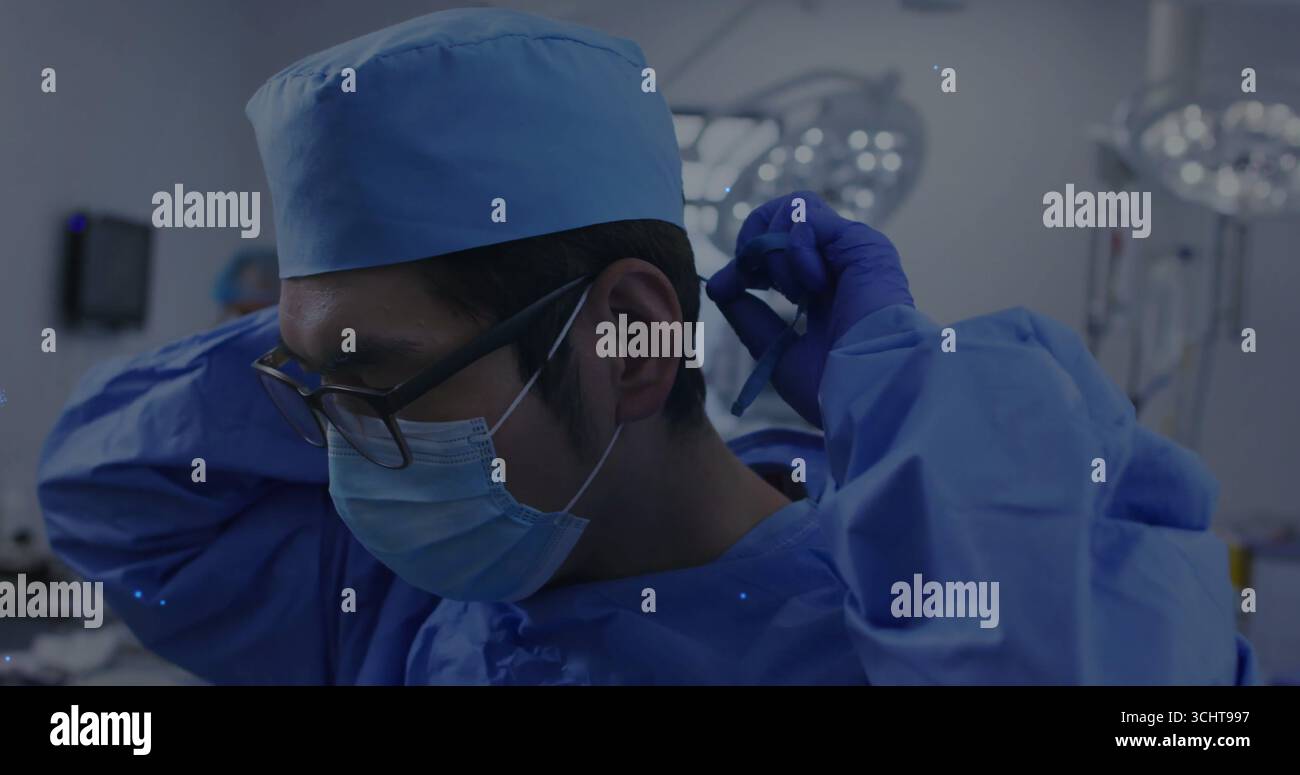 Einstellender Chirurg, OP-Kappe und Handschuhe im Operationssaal, mit Überkopflichtern Stockfoto Einstellender Chirurg, OP-Kappe und Handschuhe im Operationssaal, mit Überkopflichtern Stockfoto