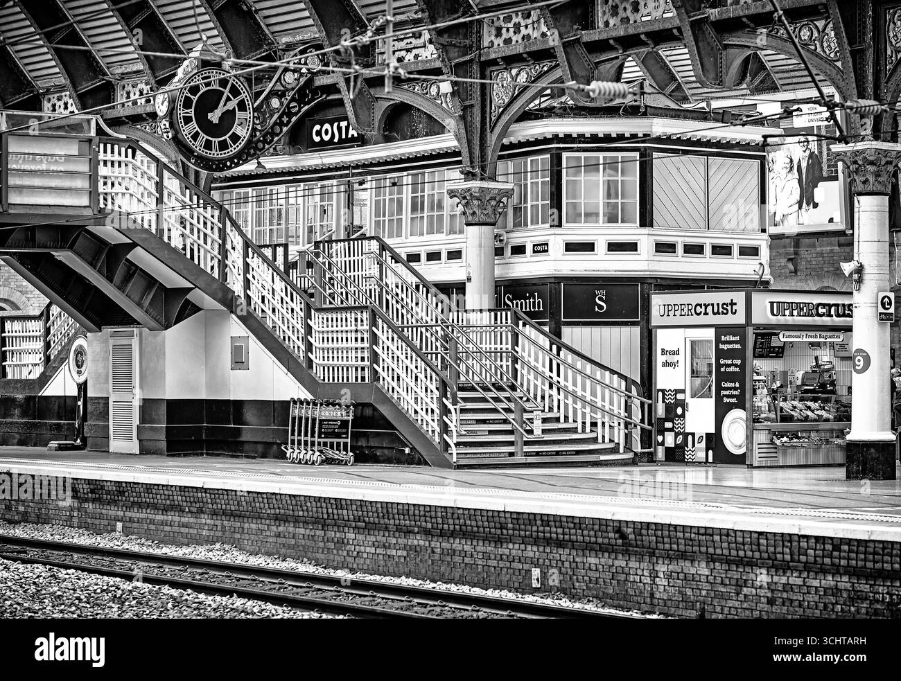 Eine Treppe führt zu einer kunstvollen Uhr und einem Café. Ein historisches eisernes Vordach aus dem 19. Jahrhundert mit architektonischen Säulen auf der Plattform. Stockfoto