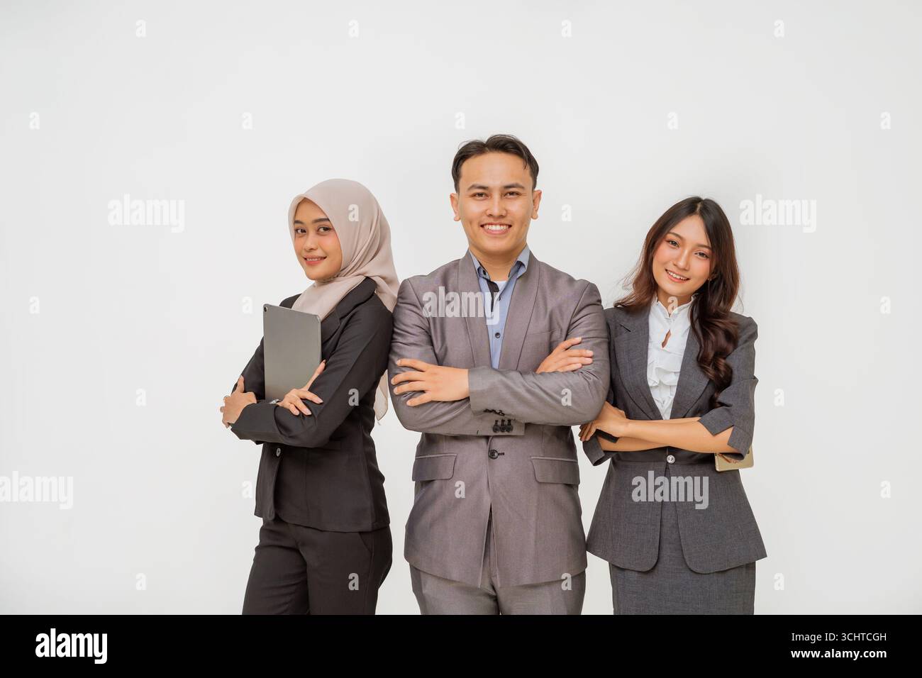 Ein vielfältiges und dynamisches Geschäftsteam in Anzügen stellt sich in einem modernen Büro selbstbewusst dar Stockfoto