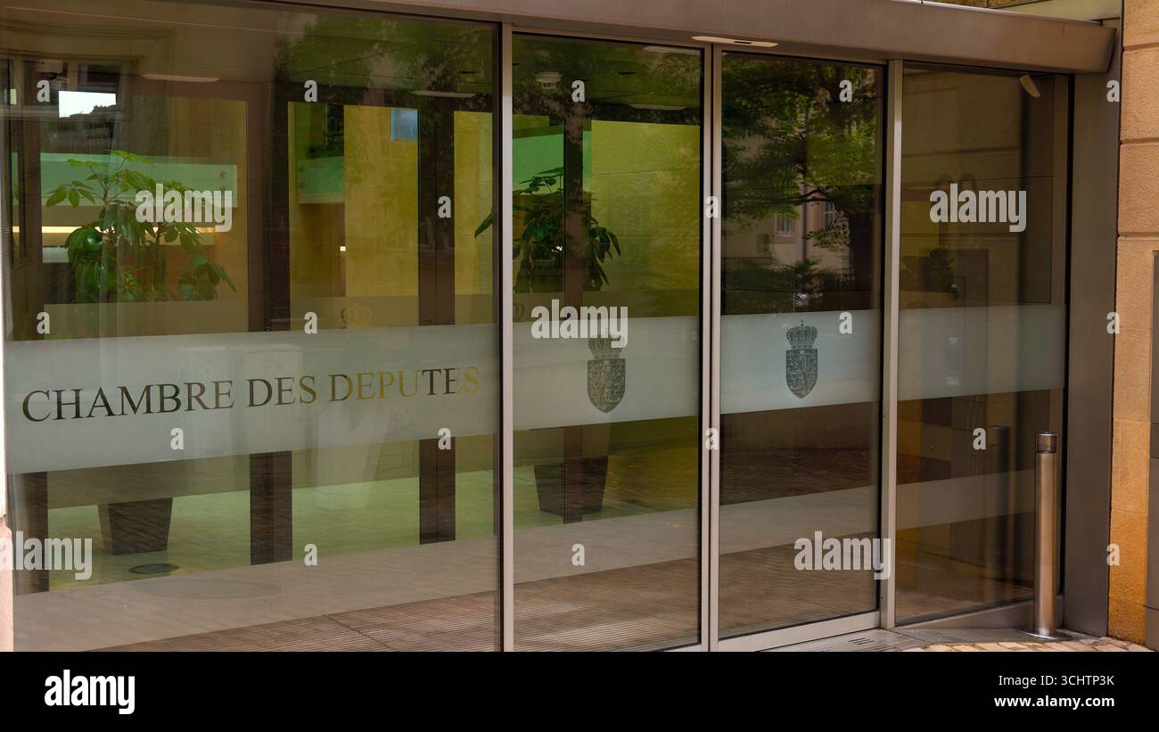 LUXEMBURG, EUROPA - 1. SEPTEMBER 2025 - Glastüren der Chambre des Deputes spiegeln umliegende Gebäude und Bäume in Luxemburg-Stadt wider Stockfoto
