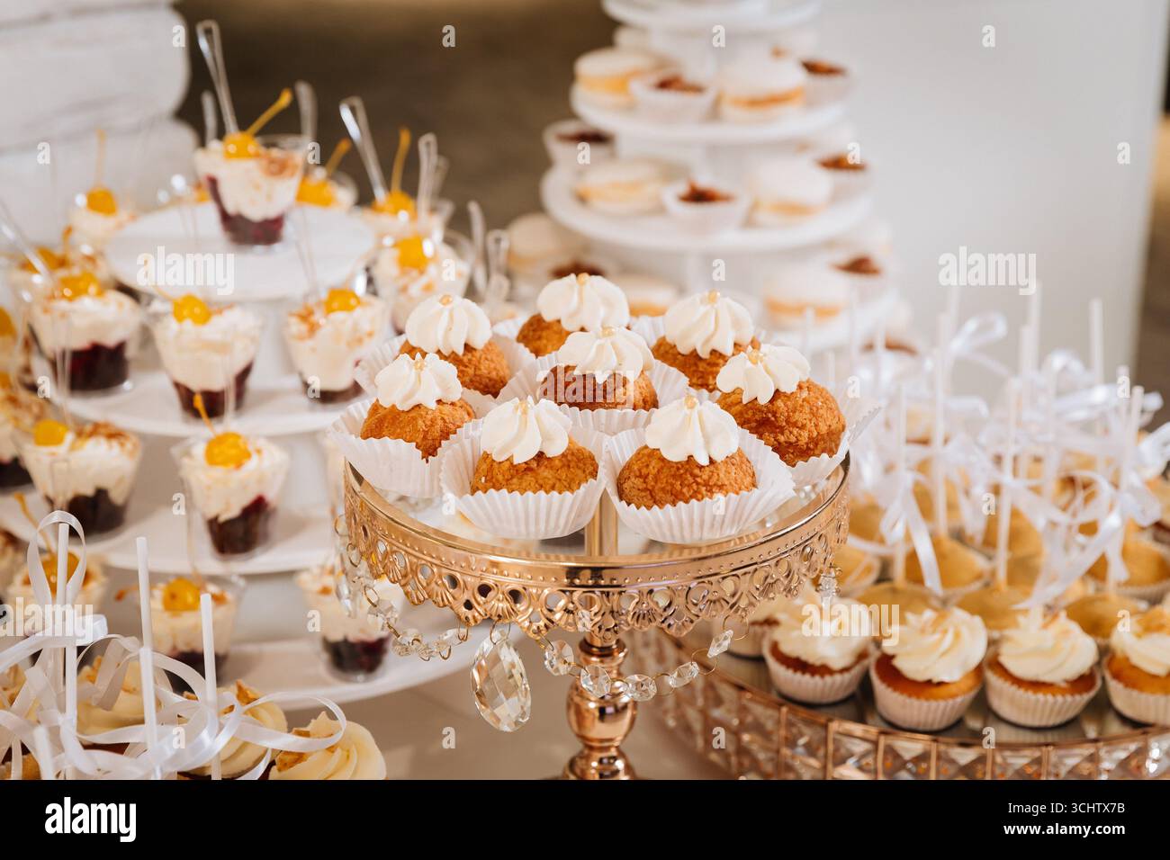 Luxuriöse Schokoriegel mit Cupcakes, Macarons und Desserts auf eleganten goldenen Tabletts Stockfoto