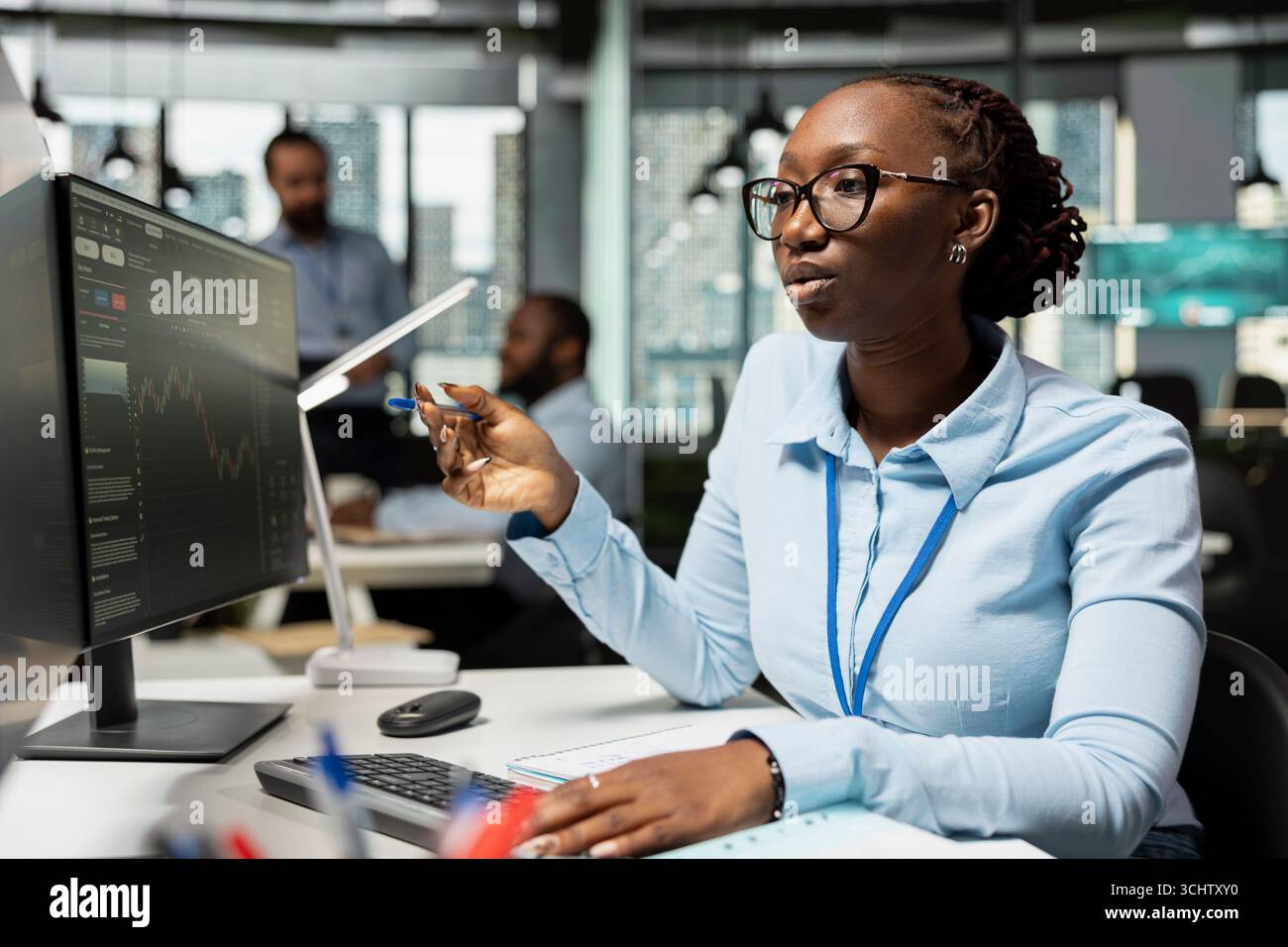 Der Risikoanalyst überwacht die Marktaktivität, um Anzeichen für Marktvolatilität zu erkennen. afroamerikanerin, die Portfolioleistungsberichte überprüft und auf potenzielle finanzielle Risiken überprüft Stockfoto