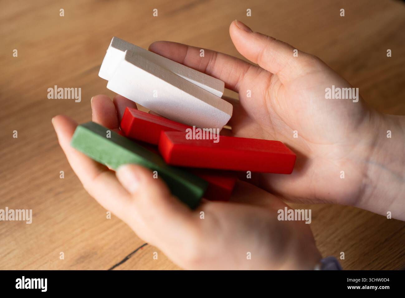 Hände halten sanft bunte Holzblöcke, symbolisieren Pflege und Halt Stockfoto