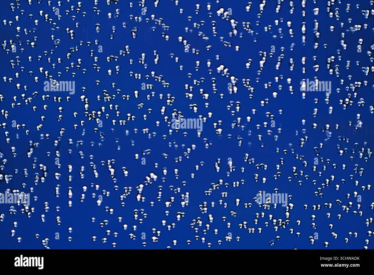 Textur von Wasser oder Metalltröpfchen auf blauem Hintergrund. Stockfoto