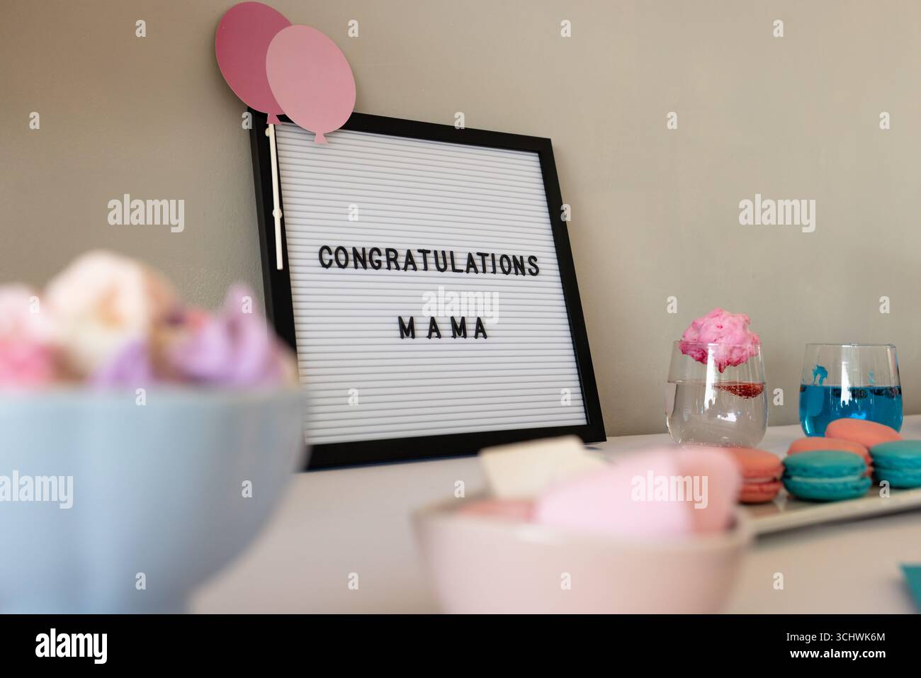 Feierliche Einrichtung mit Glückwunschschild, farbenfrohen Macarons und festlichen Getränken, zu Hause Stockfoto