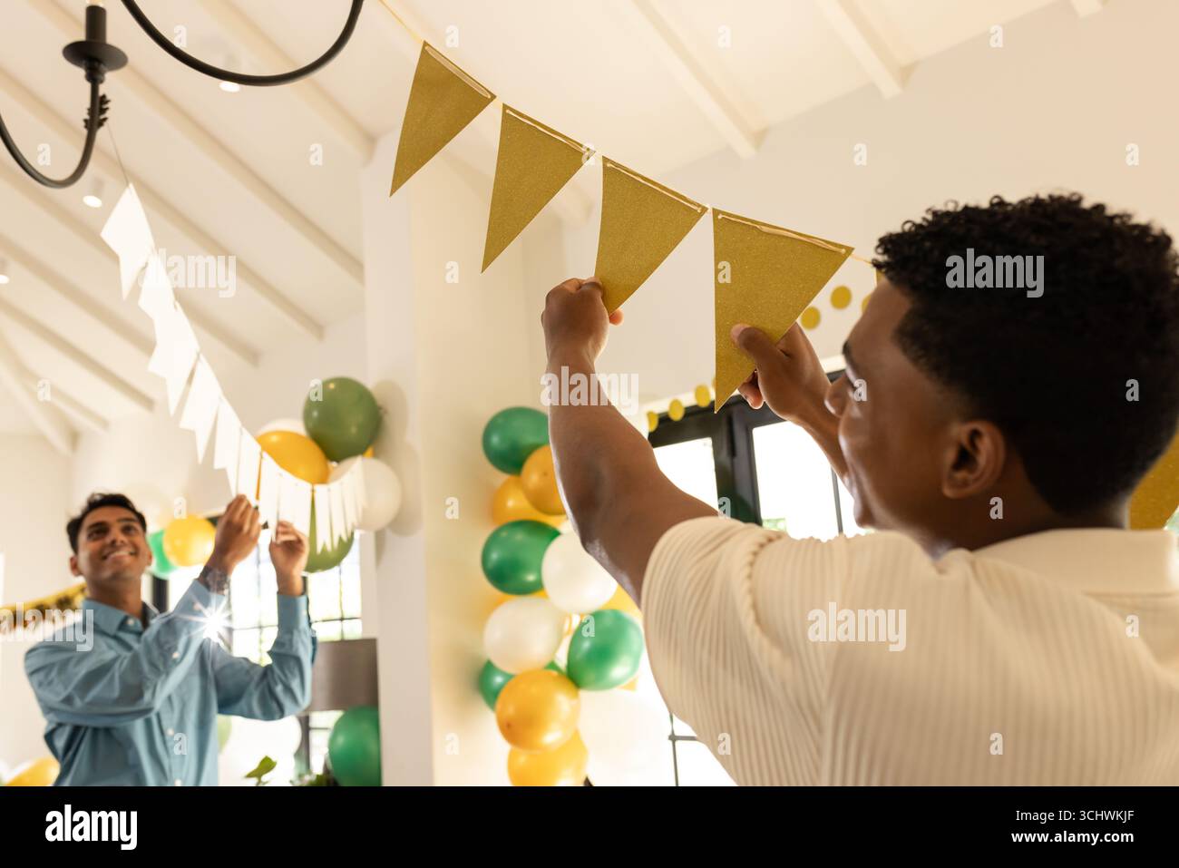 Dekoration der Party, zwei Männer hängen goldene Banner mit bunten Ballons, zu Hause Stockfoto