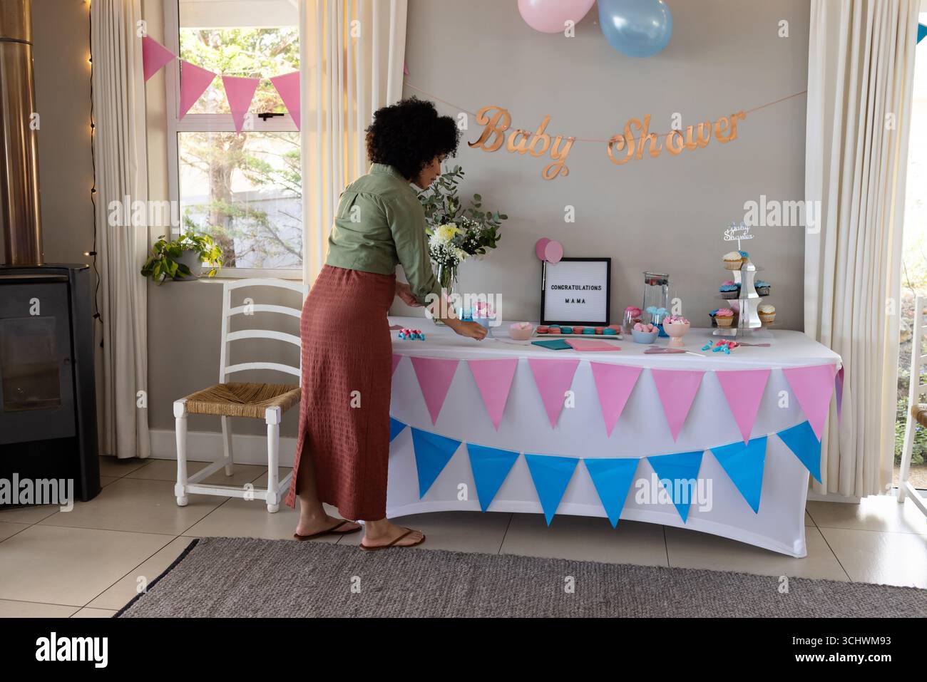 Die Babyduschtisch dekorieren, die Frau arrangiert Cupcakes und bunte Banner, zu Hause Stockfoto