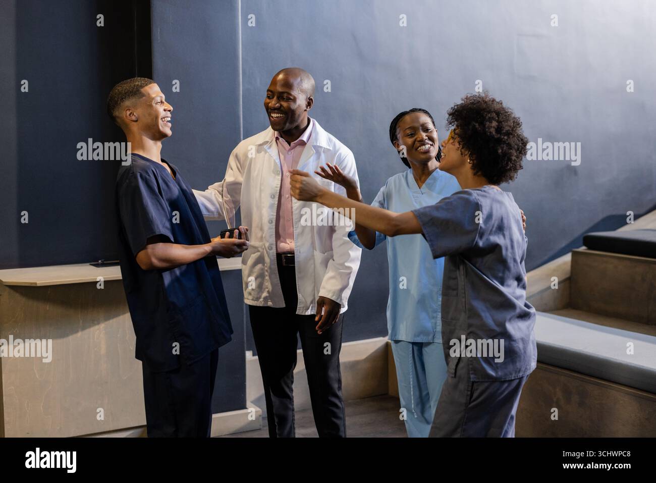 Gesundheitsfachkräfte in Peelings und Arzt im Laborkittel teilen freudige Momente Stockfoto