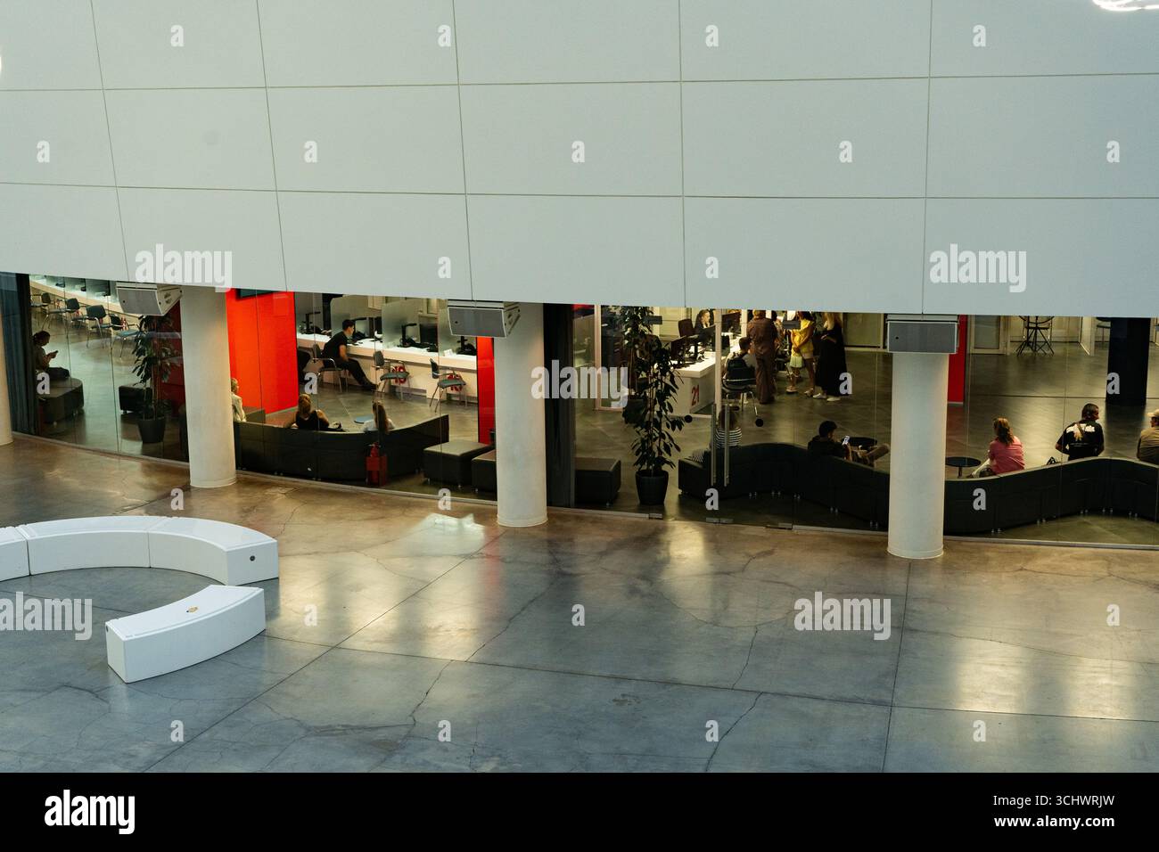 Moderner offener Innenraum mit Arbeitsbereichen für die Zusammenarbeit, heller Beleuchtung und interaktiver sozialer Interaktion zwischen Einzelpersonen in einem Shared Stockfoto