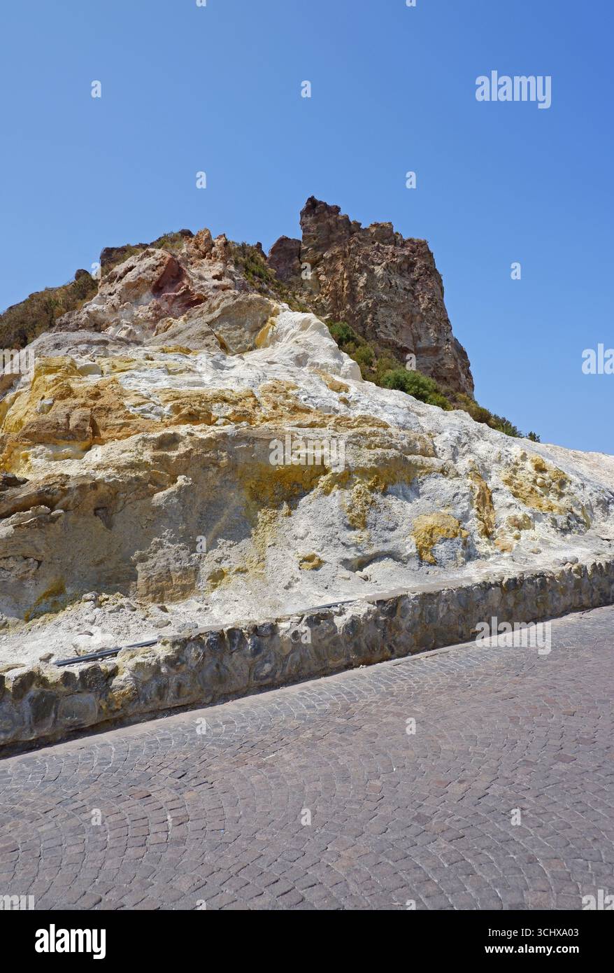 Vulkanische Schwefelgesteinsformationen auf der Seite einer Kopfsteinpflasterstraße auf der Insel Vulcano, Äolische Inseln, Sizilien, Italien Stockfoto