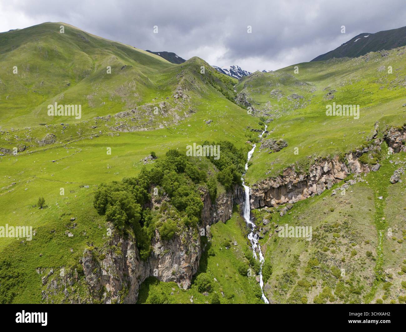 Landschaft mit langem Wasserfall zwischen grünen Bergen unter bewölktem Himmel, Blick aus der Luft, Toti Wasserfall oder Arsha Wasserfall, Arshistskhali Fluss, Kasbegi Stockfoto Landschaft mit langem Wasserfall zwischen grünen Bergen unter bewölktem Himmel, Blick aus der Luft, Toti Wasserfall oder Arsha Wasserfall, Arshistskhali Fluss, Kasbegi Stockfoto