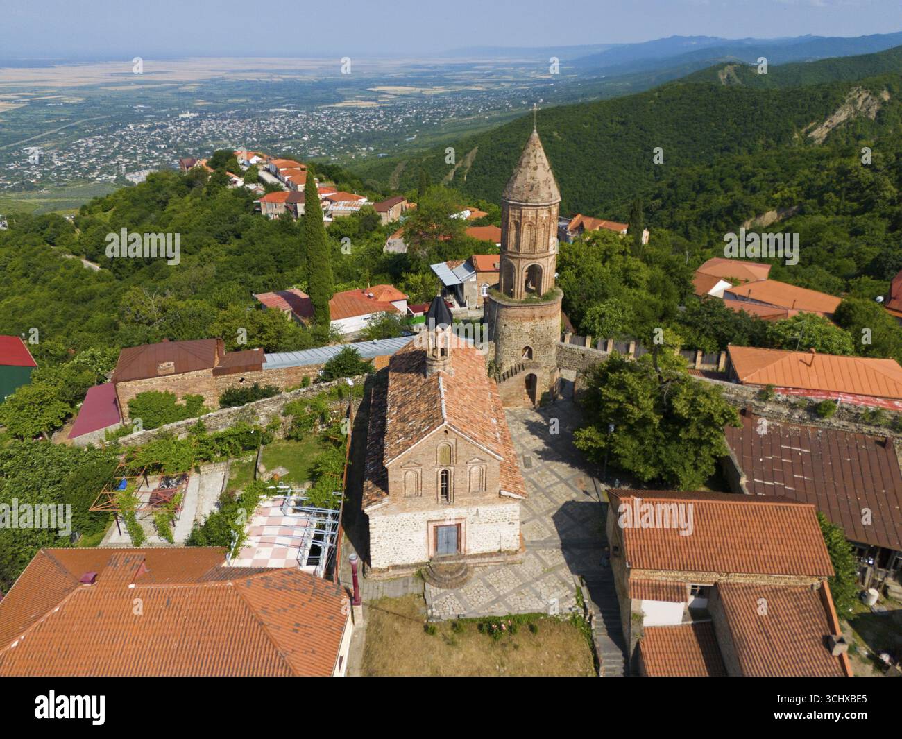 Historische Kirche mit Turm in einem Dorf umgeben von Bergen mit roten Ziegeldächern, Blick aus der Luft, Kirche St. George, St. George, Sighnaghi, Signagi Stockfoto