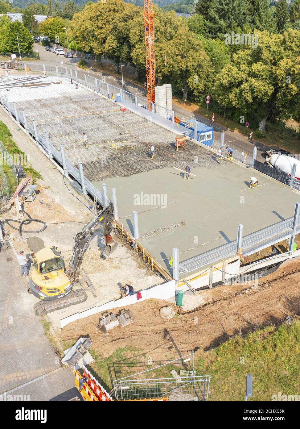 Arbeiter und Maschinen betonieren auf einer Baustelle unter einem großen Kran, Parkplatzbau, Calw, Deutschland Stockfoto