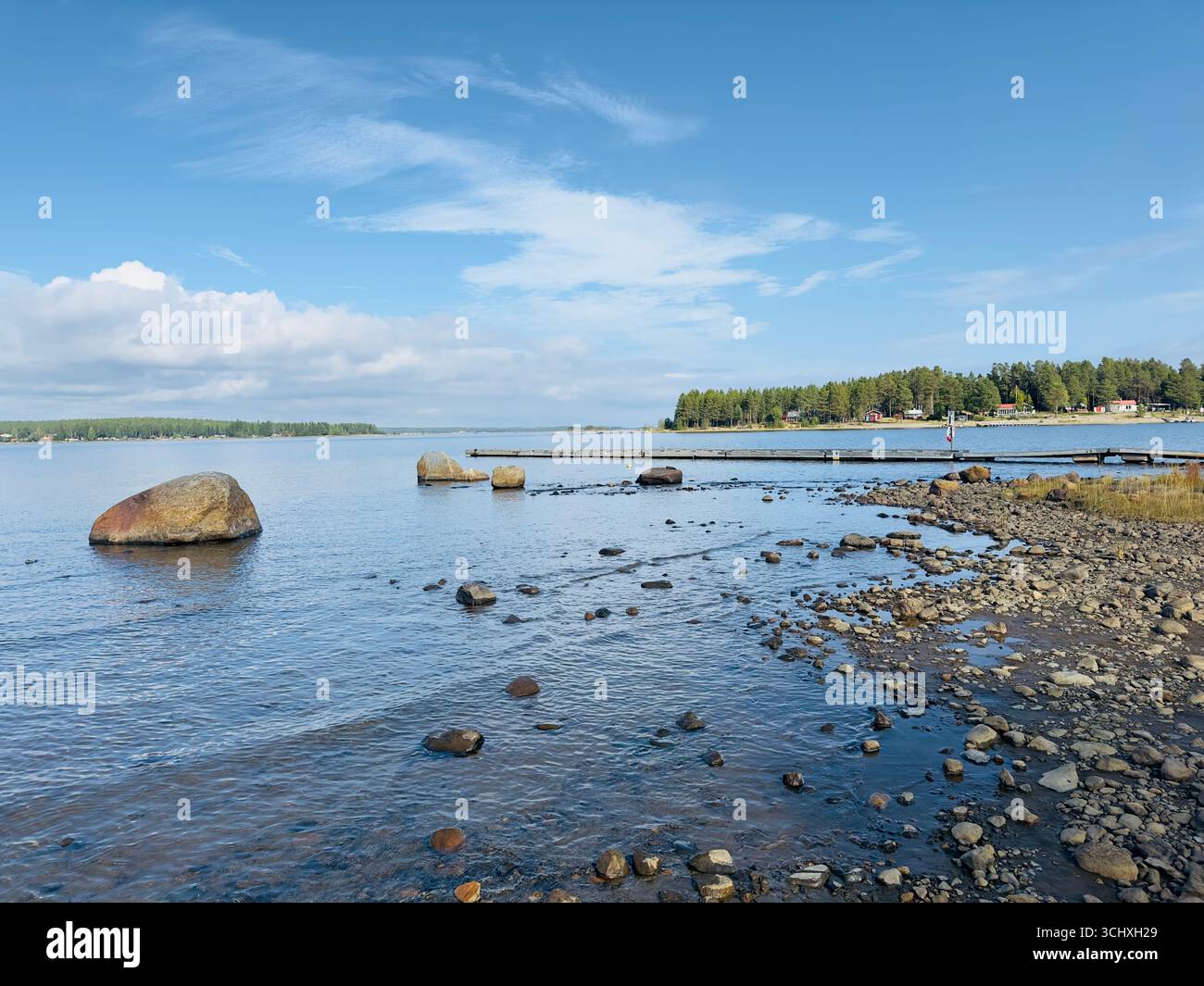 Malerischer Blick auf eine felsige Küste und ruhiges Wasser unter blauem Himmel. Stockfoto
