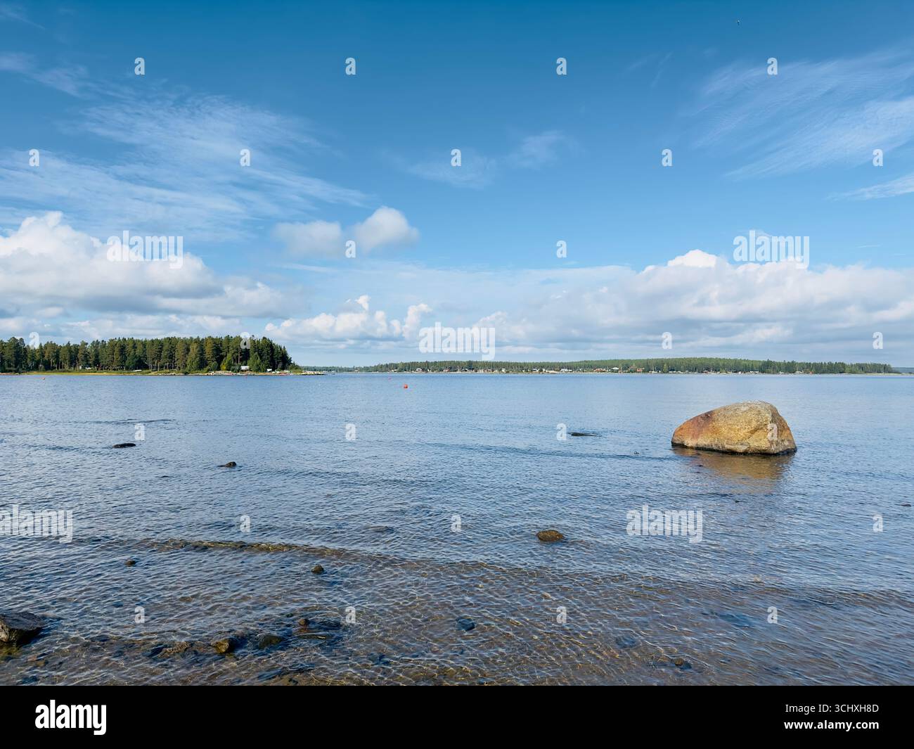 Malerischer Blick auf eine felsige Küste und ruhiges Wasser unter blauem Himmel. Stockfoto