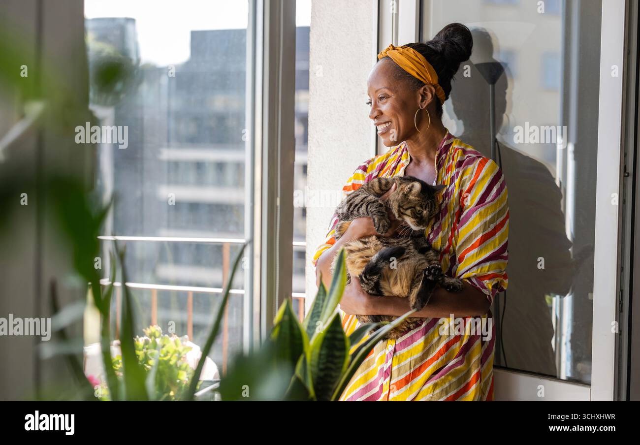 Porträt einer lächelnden Frau mit ihrer Katze zu Hause Stockfoto