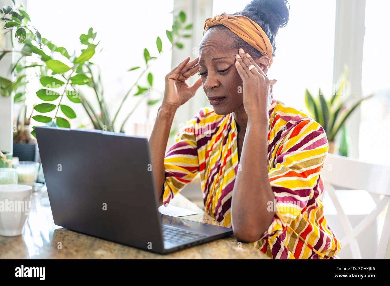 Porträt einer gestressten Frau mit Laptop zu Hause Stockfoto