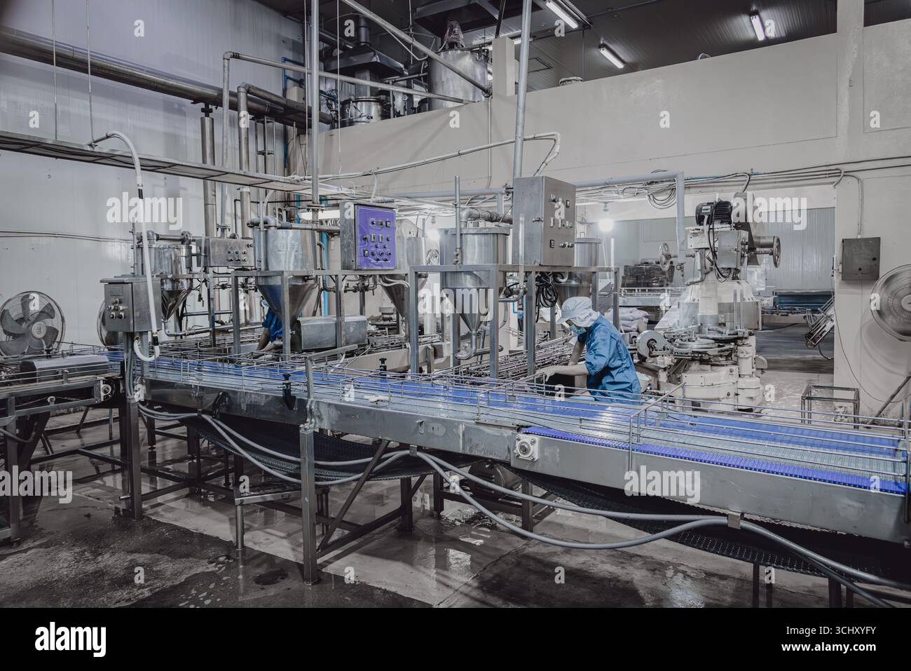 Ruhige Fabrik, wenige Werksarbeiter reinigen die Produktionslinie Förderband bereiten sich darauf vor, die Lebensmittelfabrik nachts zu schließen Stockfoto