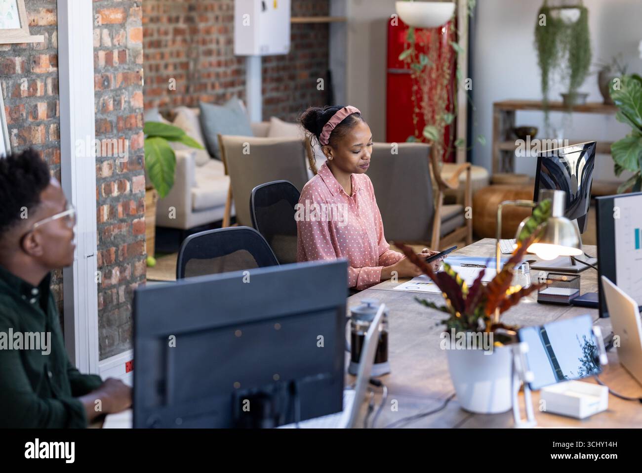 Kollegen, die an modernen Bürotischen arbeiten und sich auf digitale Projekte konzentrieren Stockfoto
