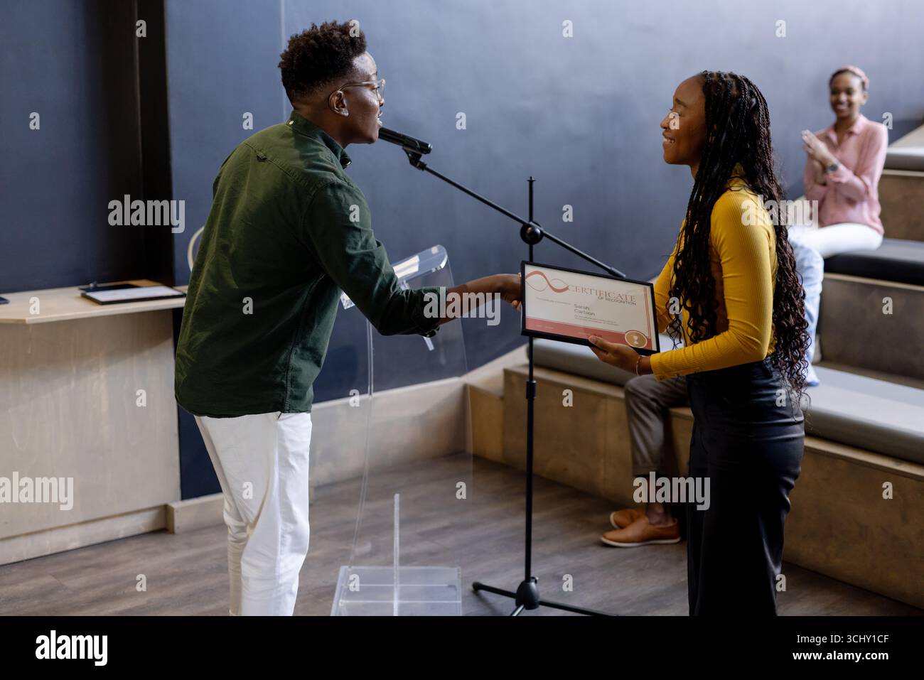 Auf der Bühne wurde die junge Frau vom Publikum im modernen Büro applaudiert Stockfoto