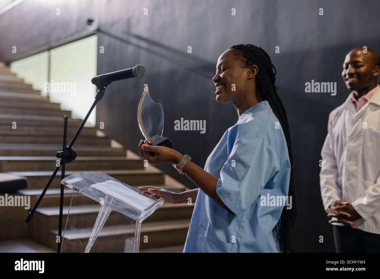 In der Schule hat afrikanische Frau in blauem Scrubs eine Auszeichnung gehalten und selbstbewusst gesprochen Stockfoto