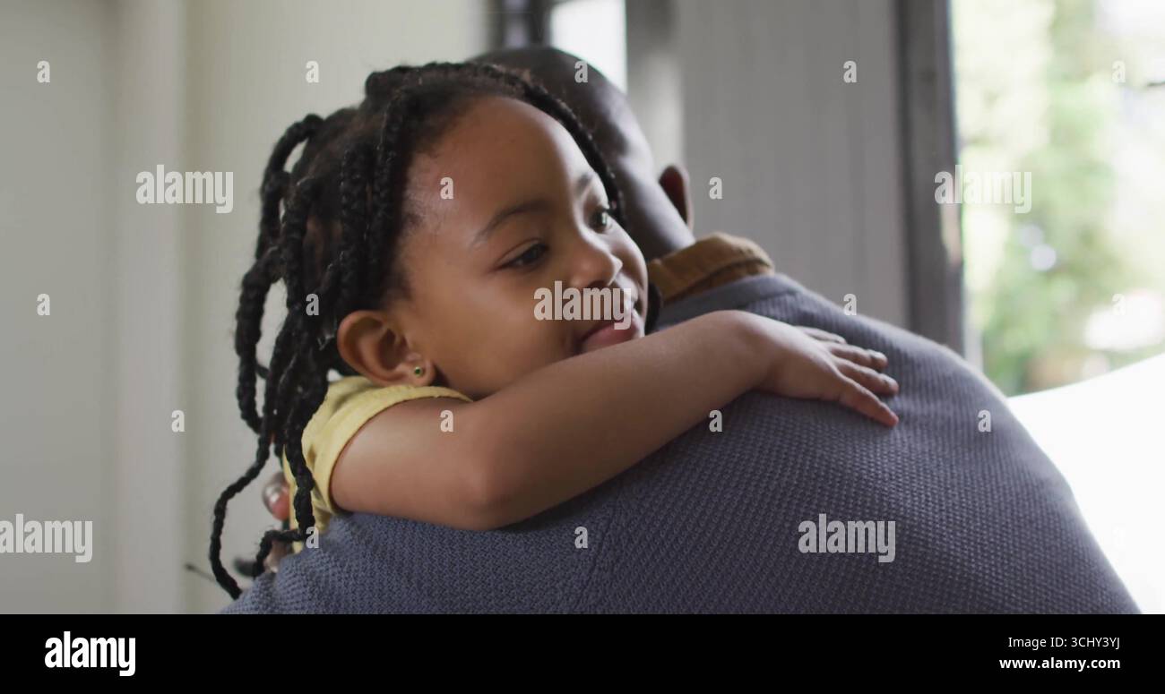 Mann, der das Kind über die Schulter umarmt und sicher zu Hause in der Nähe des Fensters hält, Familienbindung Stockfoto