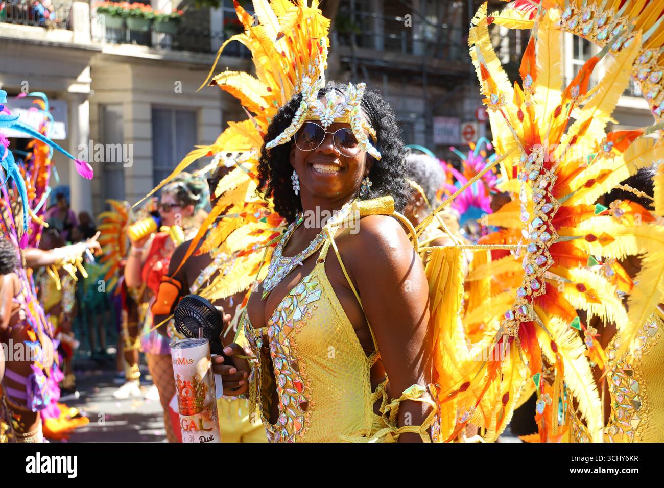 Ein Mädchen in Gelb posiert glücklich beim Notting Hill Carnival in London, Großbritannien. Stockfoto